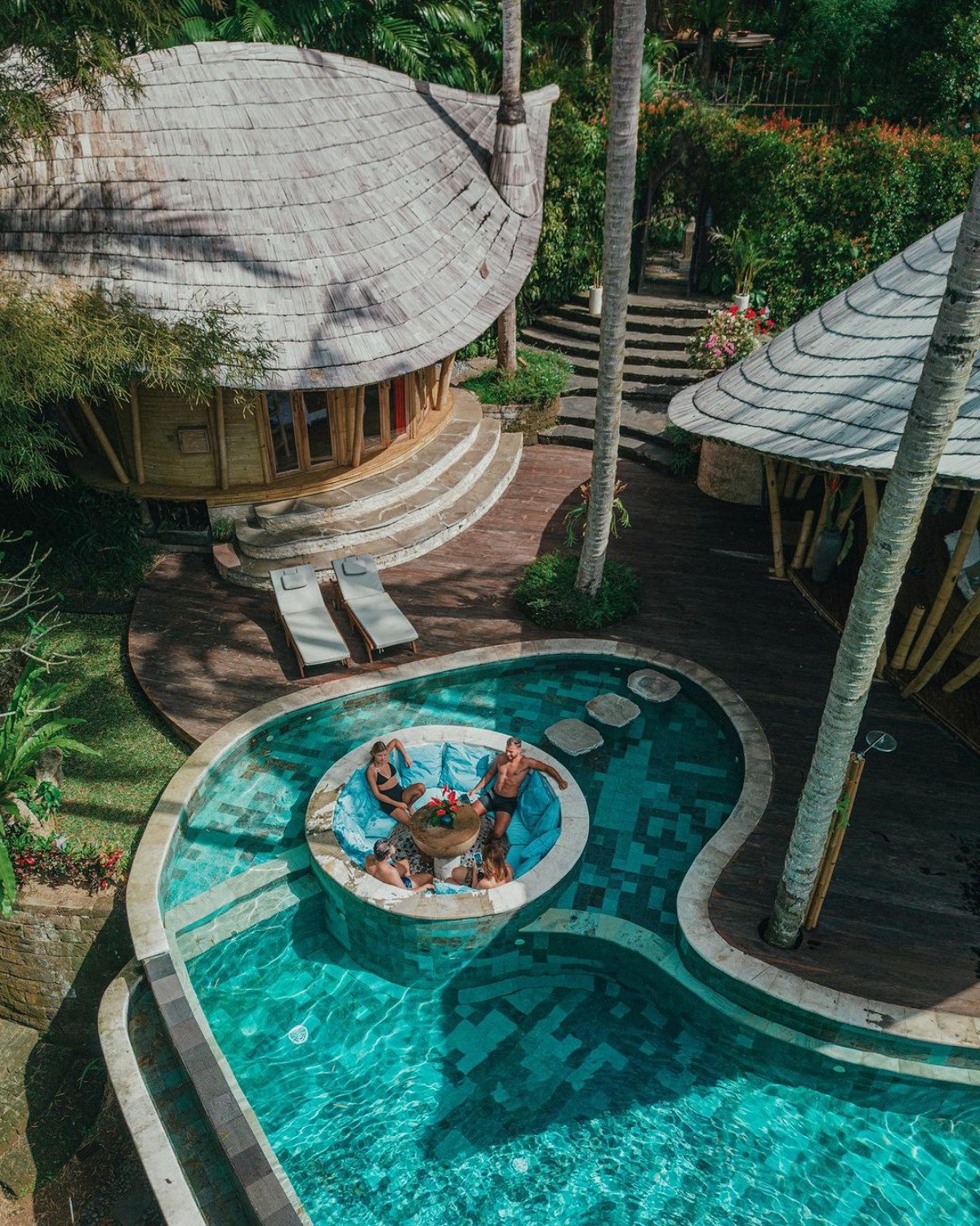 Bamboo eco-house overlooking a unique pool with guests lounging in Ubud, Bali.